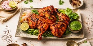 Tandoori grilled chicken platter with lemon slices, salad, and green chutney served at the best Indian restaurant in Singapore.